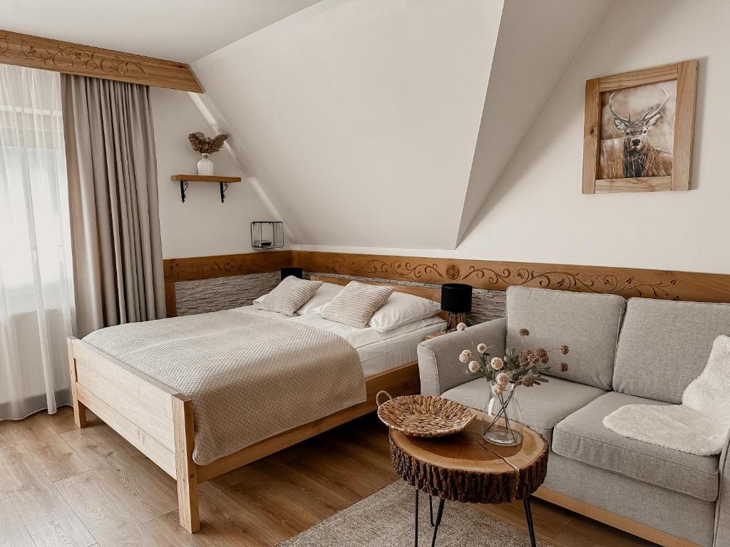 a bedroom with a bed and a couch and a table at Willa Bliźniaczek in Zakopane