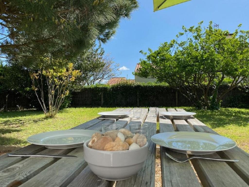 une table de pique-nique en bois avec des assiettes et un bol de nourriture dans l'établissement la Petite Seibel, à Les Bussolleries