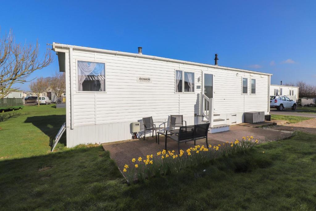 a white house with a table and chairs in a yard at Flosh Caravan in Maryport