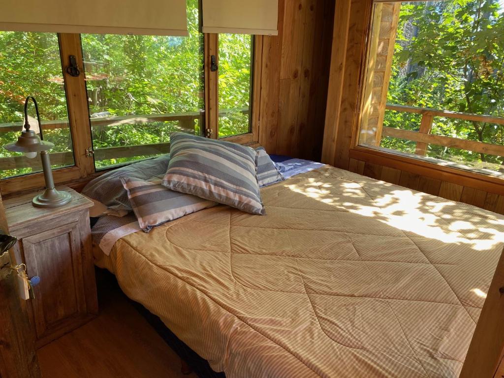 a bedroom with a bed in front of a window at Casita del Arbol Santa Clara in San Carlos de Bariloche