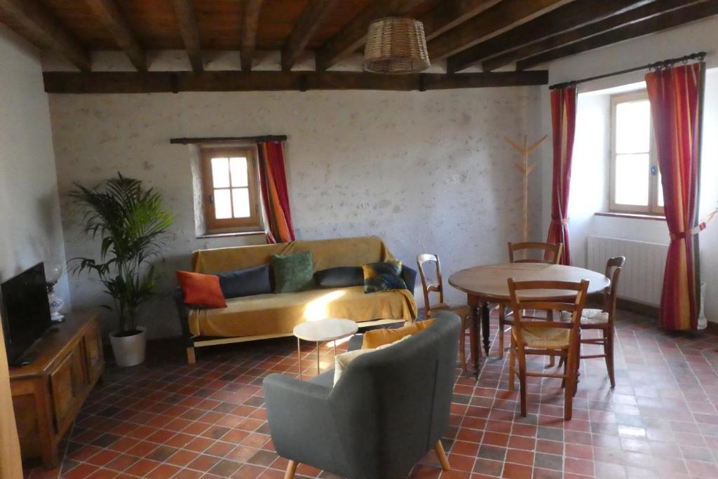 a living room with a couch and a table at A la croisée des châteaux 3 étoiles in Ouchamps