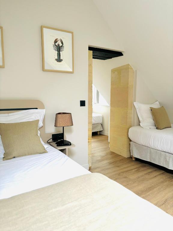 a bedroom with two beds and a lamp in it at Hôtel De La Marine in Arromanches-les-Bains