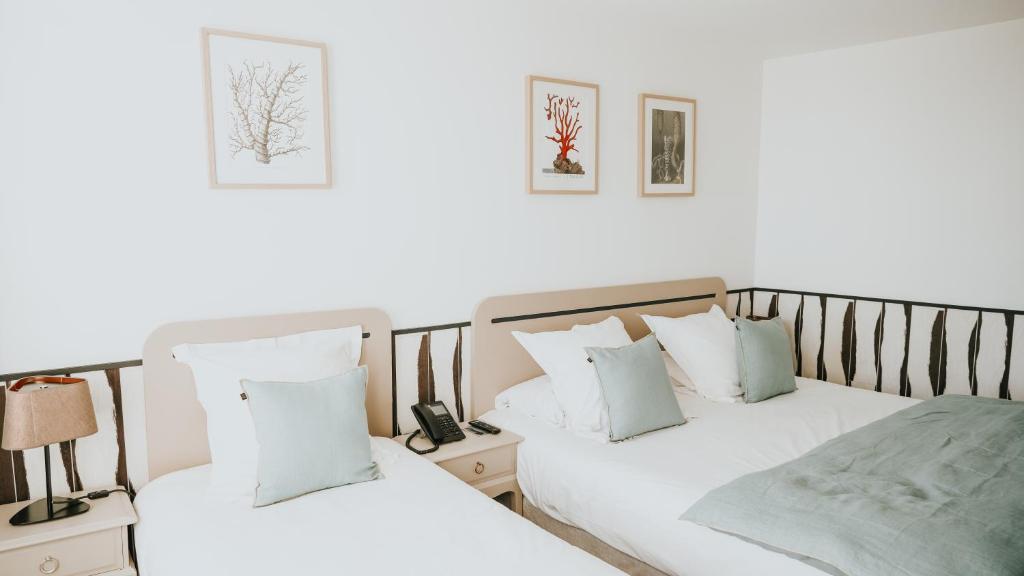 two beds sitting next to each other in a bedroom at Hôtel De La Marine in Arromanches-les-Bains
