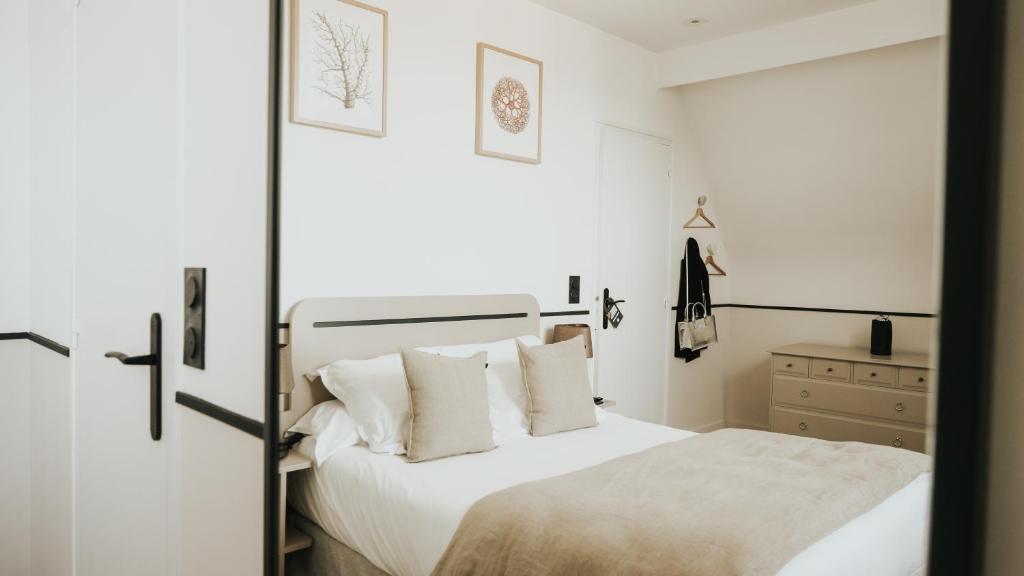a bedroom with a bed with white sheets and pillows at Hôtel De La Marine in Arromanches-les-Bains