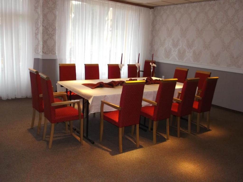 a dining room with a table and red chairs at Holiday Park Orava - Hotel Orava in Dolný Kubín