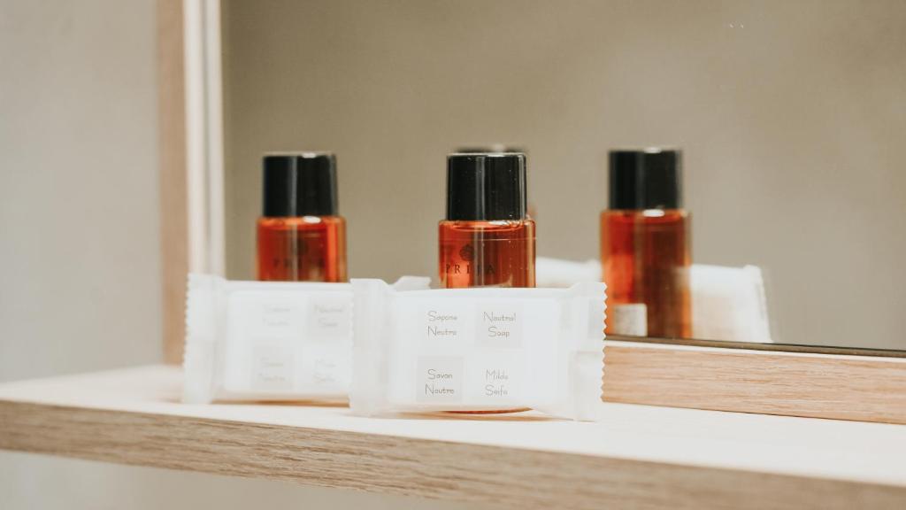 three bottles of essential oils on a shelf in front of a mirror at Hôtel De La Marine in Arromanches-les-Bains