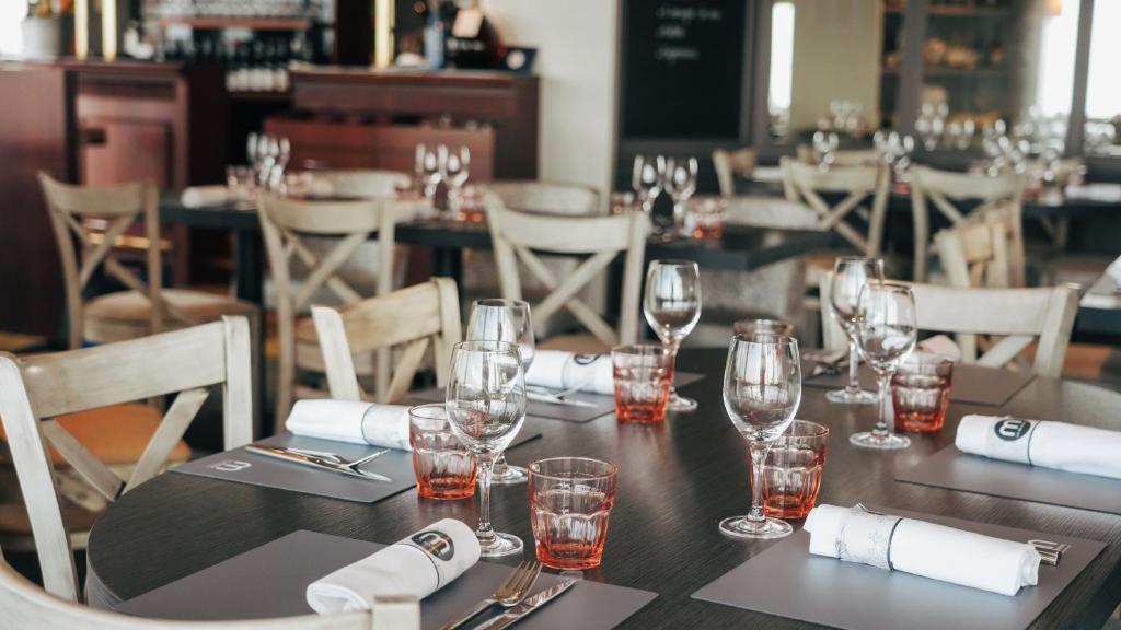 a table in a restaurant with glasses and napkins at Hôtel De La Marine in Arromanches-les-Bains