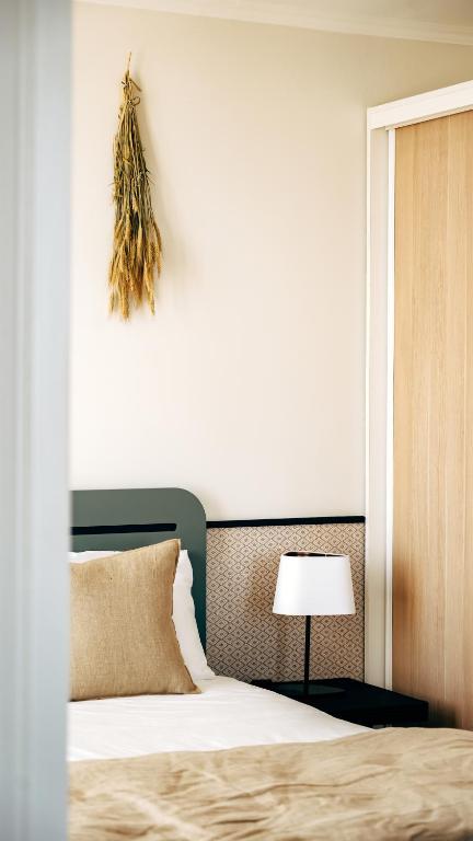 a bedroom with a large bed and a lamp at Hôtel De La Marine in Arromanches-les-Bains