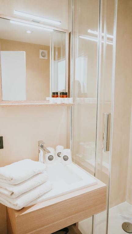 a bathroom with a white sink and a shower at Hôtel De La Marine in Arromanches-les-Bains