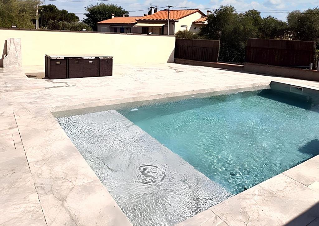 uma piscina num pátio com água azul em Villa de 7 chambres avec piscine privee jardin clos et wifi a Laroque des Alberes em Laroque-des-Albères