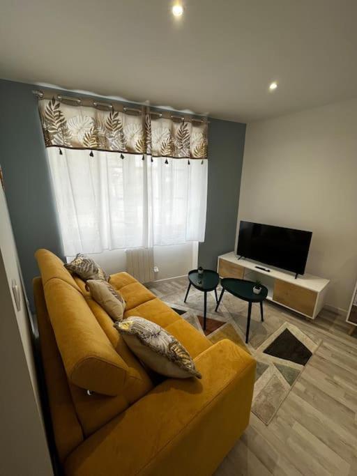 a living room with a yellow couch and a television at La maison castelpontine studio in Pont-du-Château