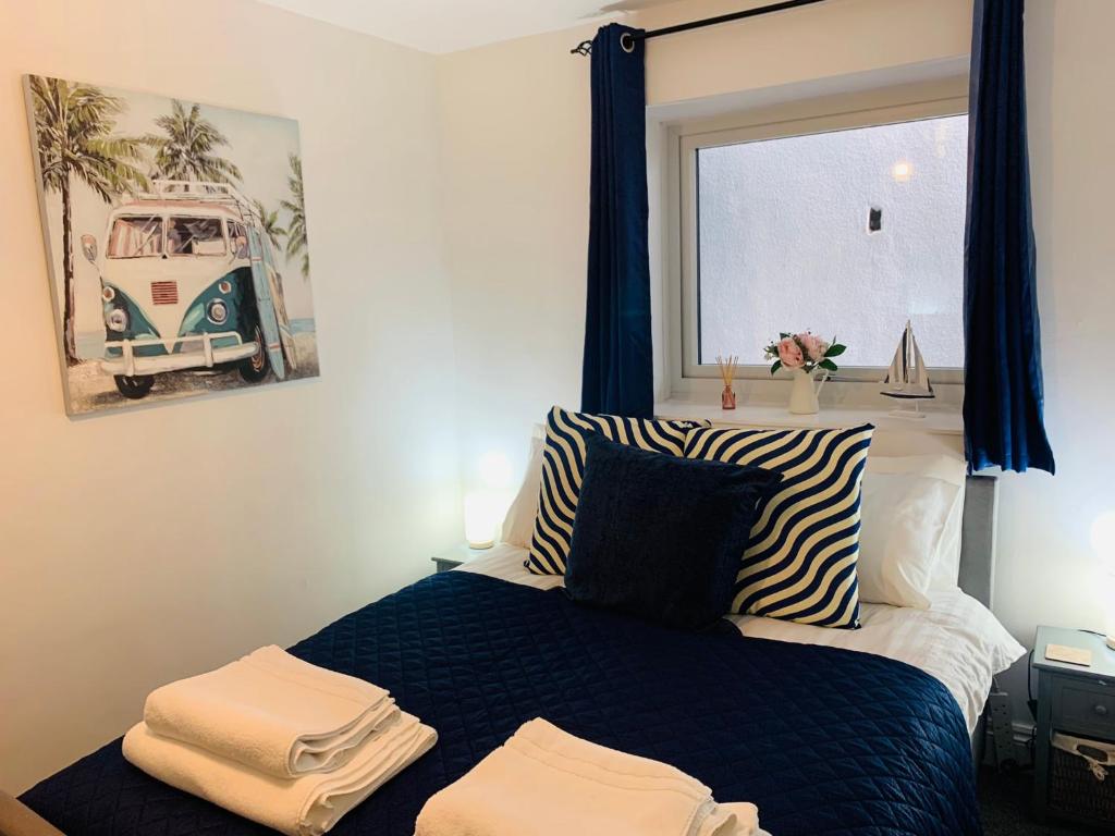 a bedroom with a bed with blue curtains and a window at Captain's Keep - Brixham in Brixham