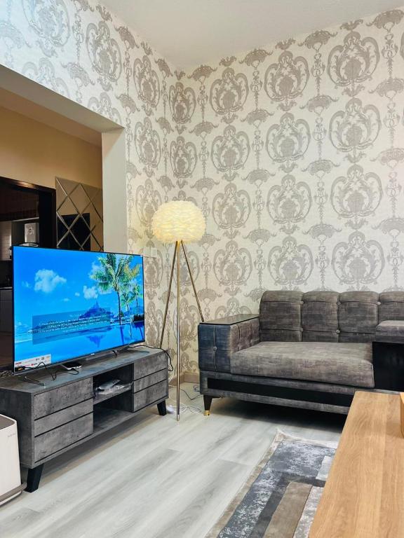 sala de estar con sofá y TV de pantalla plana en فيلا السلطان villa alsoltan, en Al Ula