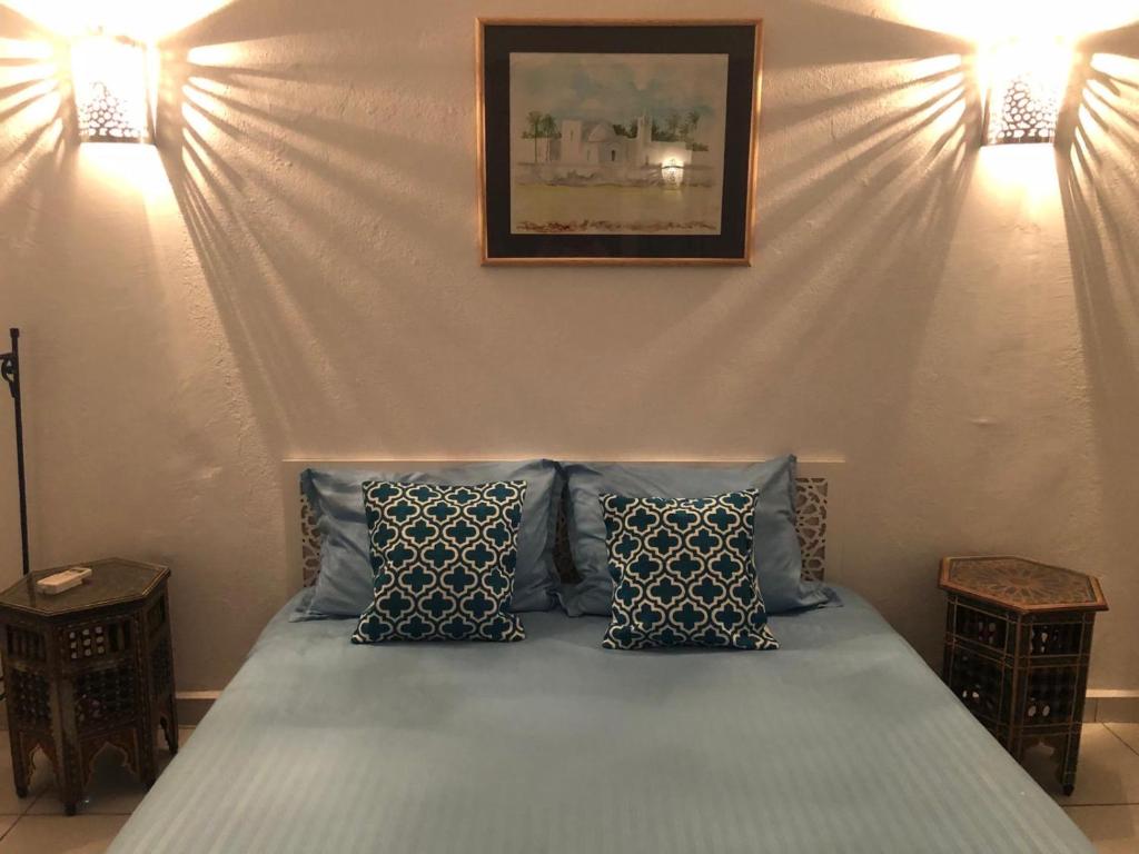 a bedroom with a bed with blue pillows at RESIDENCE DAR YASMINa in Mezraya