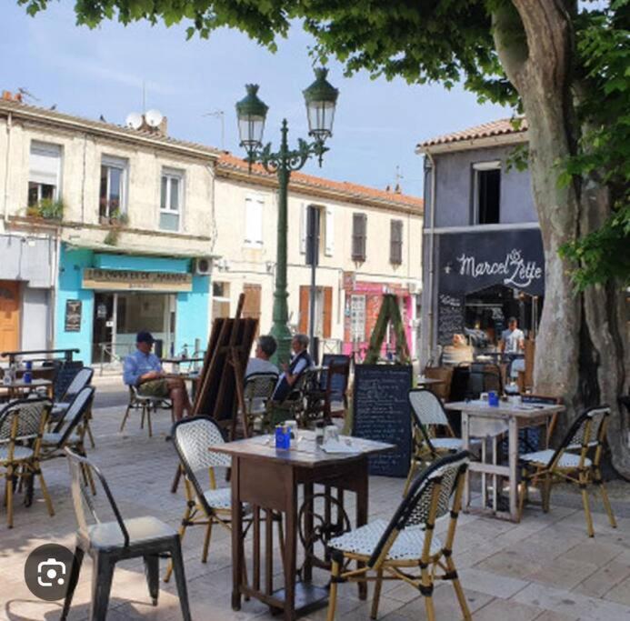 ein Café im Freien mit Tischen, Stühlen und einem Baum in der Unterkunft Magnifique Maison de Village aux abords des Calanques in Marseille