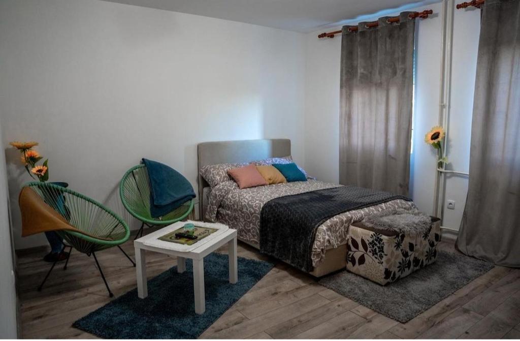 a bedroom with a bed and a table and chairs at Tea Apartman Obrenovac in Obrenovac