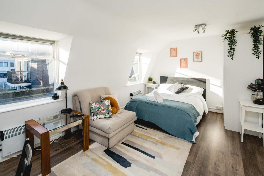 a bedroom with a bed and a chair and a window at Bright Fitzrovia Studio in London