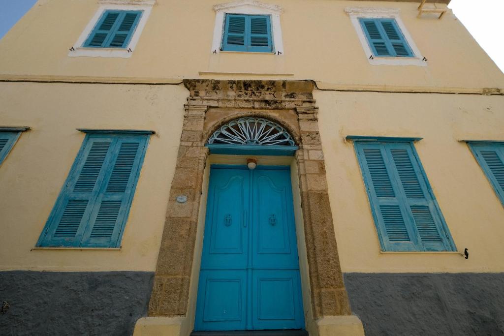 a building with a blue door and windows at Archontiko Pataka in Rhodes Town