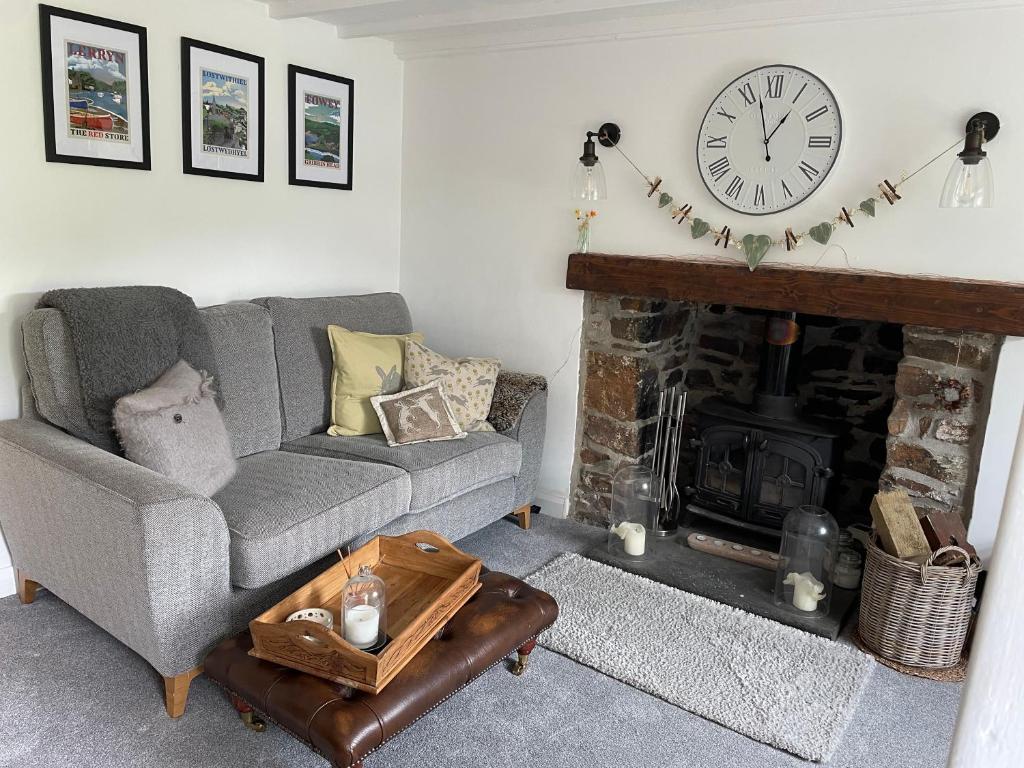 a living room with a couch and a fireplace with a clock at Tiny romantic cottage for two. in Lostwithiel