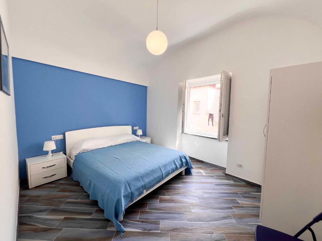 ein blaues Schlafzimmer mit einem Bett und einem Fenster in der Unterkunft Casa vacanze centro storico Procida in Procida