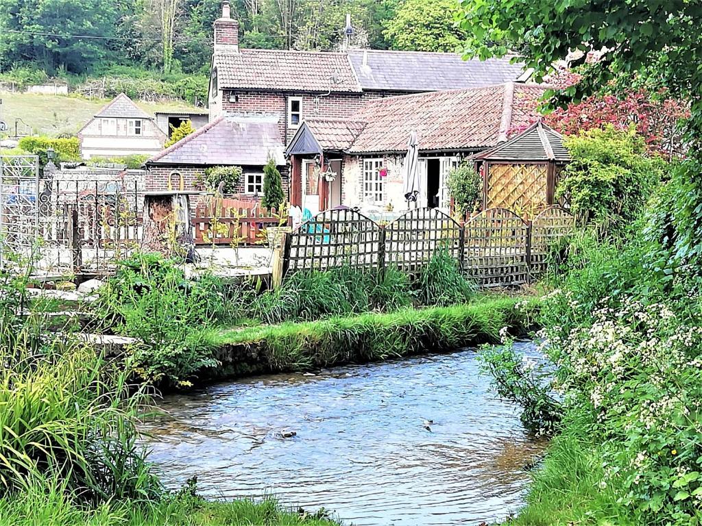 a house with a fence next to a river at escape the ordinary - private self catered holiday home stay in Dorchester