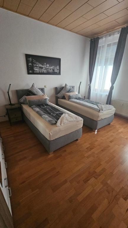 two beds in a room with a wooden floor at Suite Toni in Bernburg