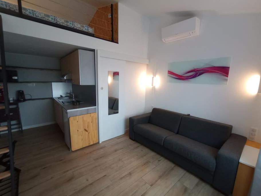 een woonkamer met een bank en een keuken bij studio Indépendant et climatisé. arrivée autonome in Bègles
