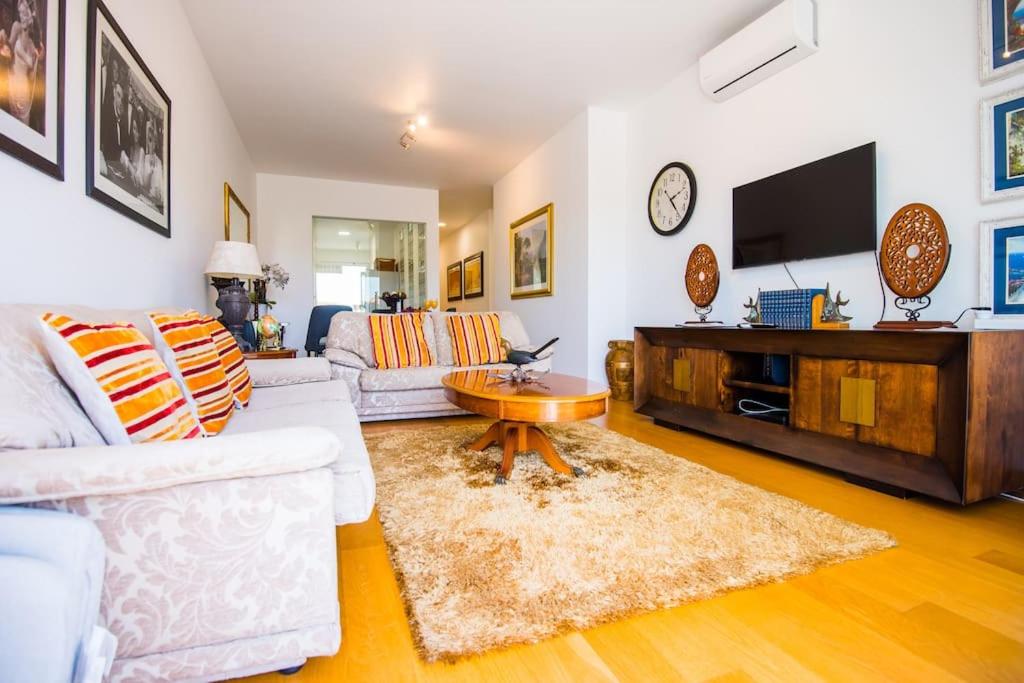 Una sala de estar con un sofá blanco y un televisor. en Santino Apartment, en Caniço