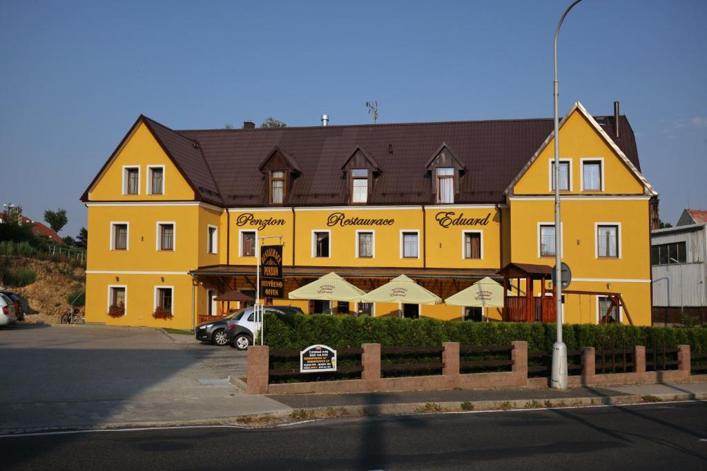duży żółty budynek z samochodem zaparkowanym przed nim w obiekcie Penzion Eduard we Franciszkowych Łaźniach