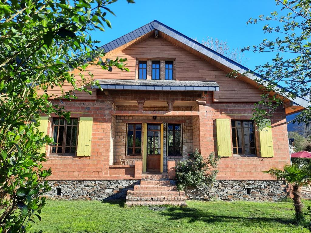 a brick house with yellow shutters on it at La VILLA Luchonaise in Luchon