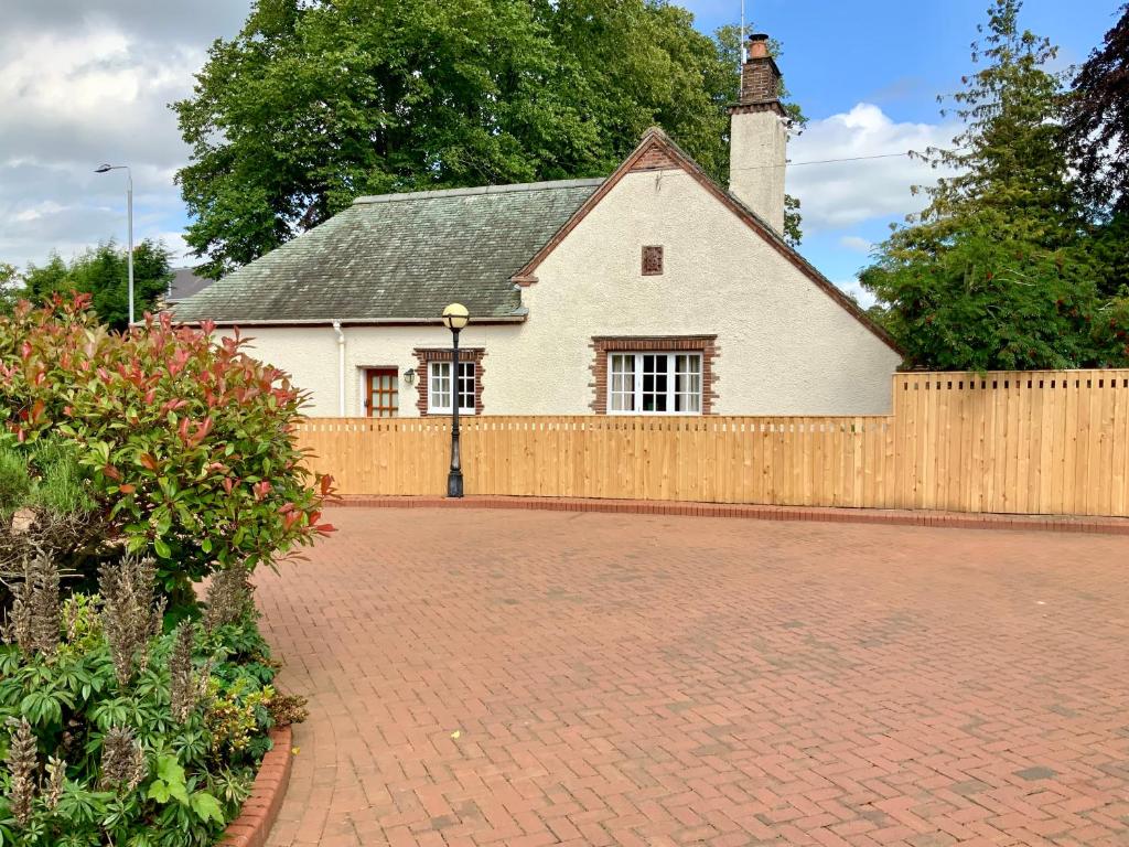 a white house with a fence and a brick driveway at Cottage in Ayr