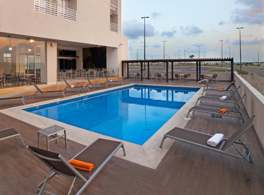 uma piscina com espreguiçadeiras e um edifício em Hotel Yes Inn Nuevo Veracruz em Veracruz