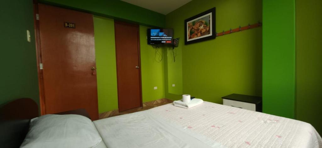 a bedroom with green and green walls and a bed at Hostal Nochero's in Tacna