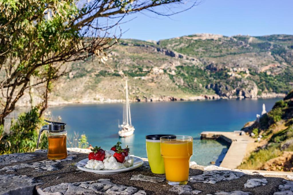 a table with two glasses of beer and a plate of food at Porto Kale Guesthouse in Porto Kagio