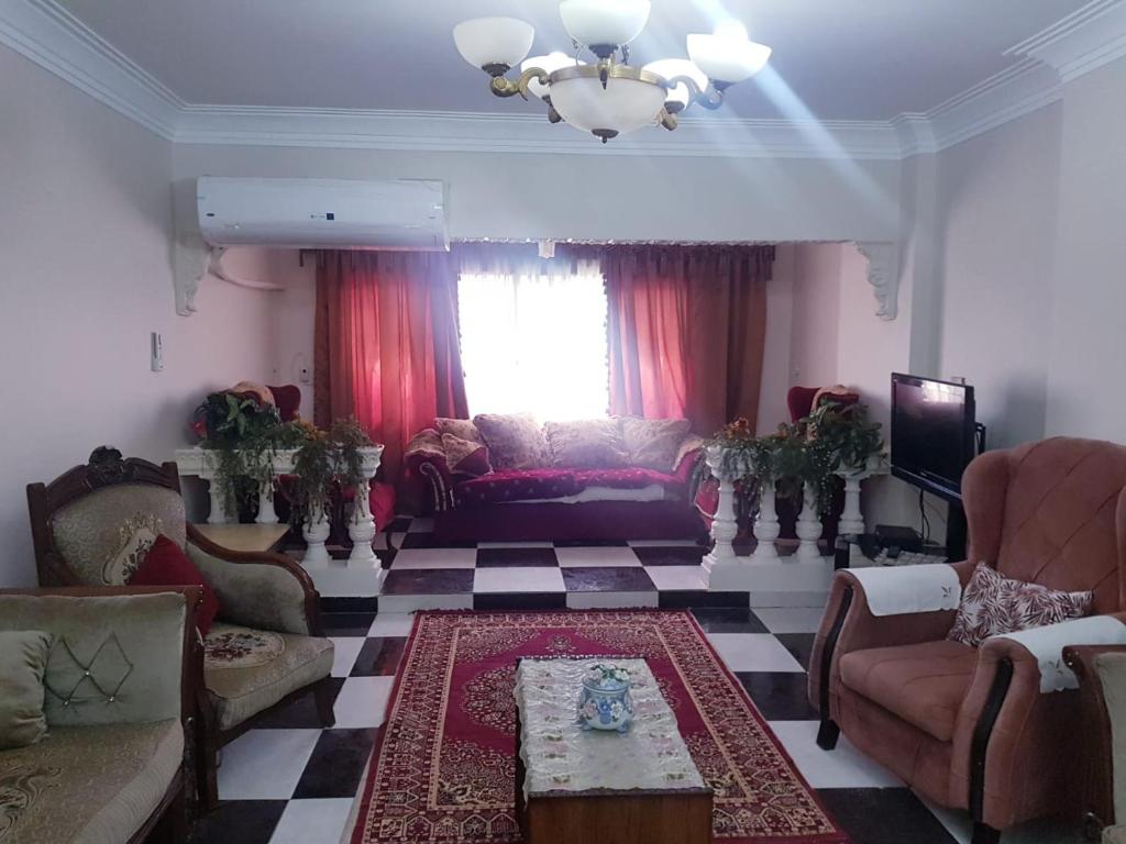 een woonkamer met een bank en stoelen en een tv bij الياسمين تاور * Jasmin Tower in Caïro