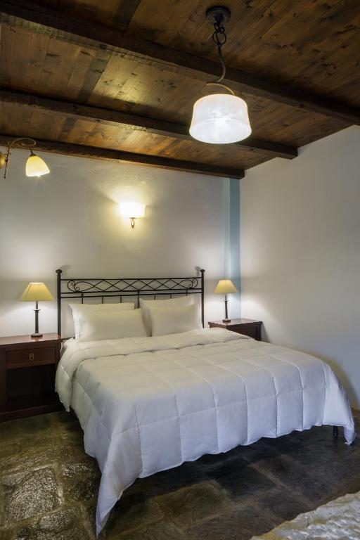 a bedroom with a large white bed with two lamps at Porto Kale Guesthouse in Porto Kagio
