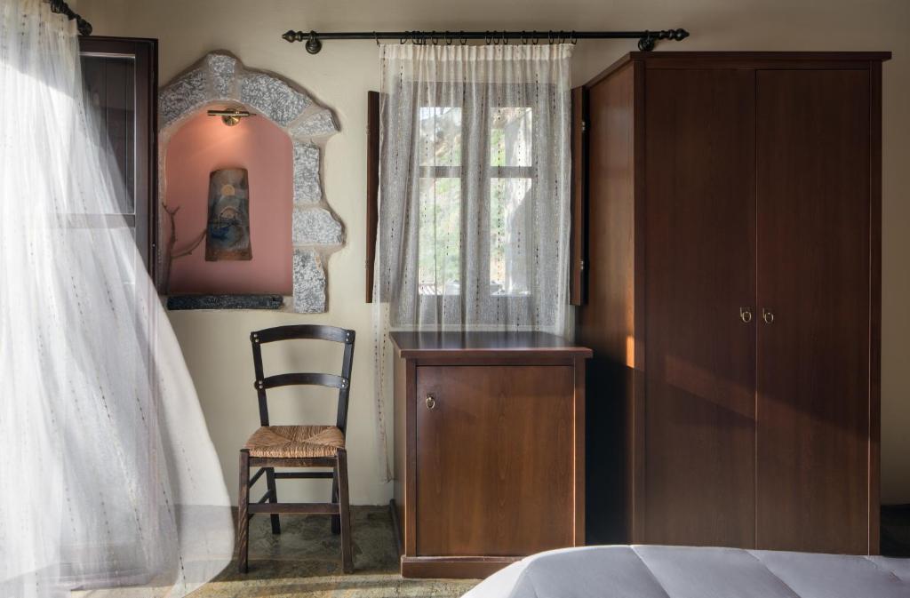 a bedroom with a bed and a chair and a window at Porto Kale Guesthouse in Porto Kagio