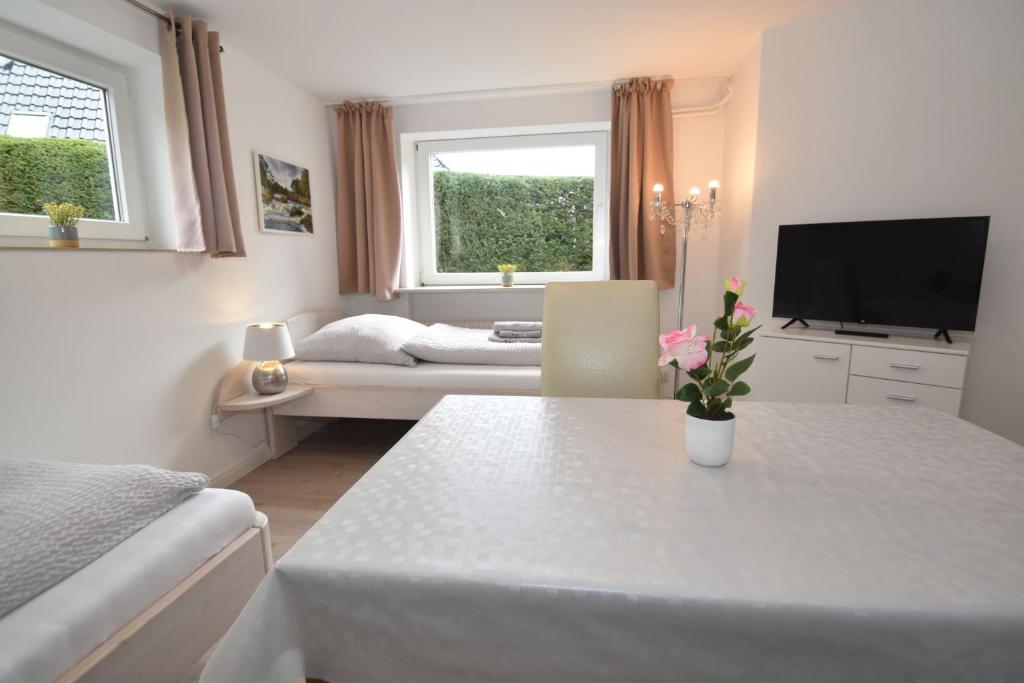 sala de estar blanca con mesa y TV en fewo1846 - Monteurswohnung Fuchsbau - preiswerte Wohnung mit 3 Schlafzimmern, en Flensburg