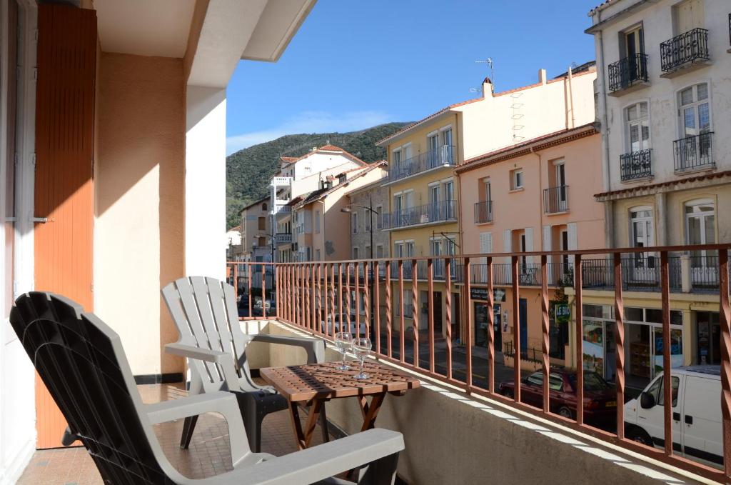 - un balcon avec des chaises, une table et des bâtiments dans l'établissement T3 VALLESPIR AMELIE LES BAINS, à Amélie-les-Bains-Palalda