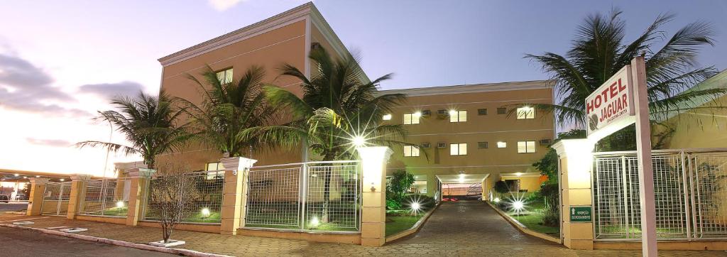 a building with gates and palm trees in front of it at Hotel Jaguar in Uberaba