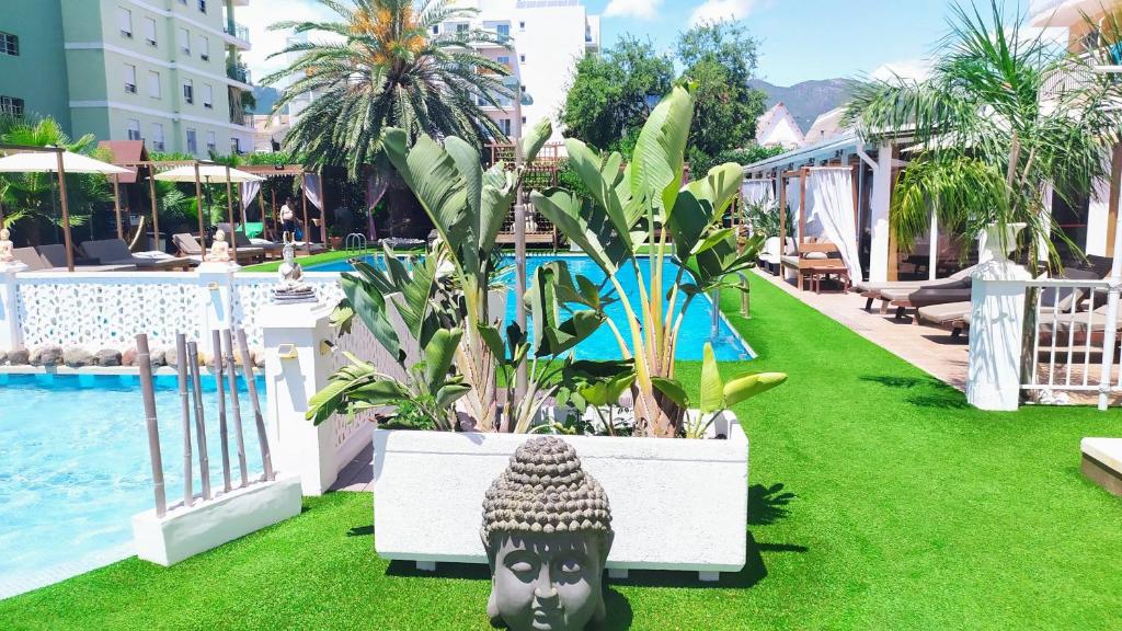 a resort yard with a pool and plants and a statue at Montreal in Benicàssim