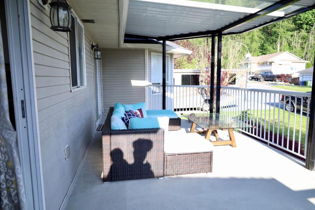 a patio with a couch and a table on a porch at Sandy Hill Retreat - 3 Bedroom + Den, 2 Bath House with Fitness Equipment in Abbotsford