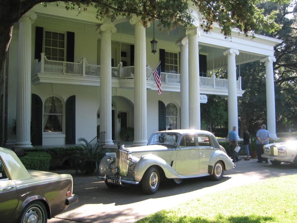 een oude auto geparkeerd voor een wit huis bij Belle Oaks Inn in Gonzales