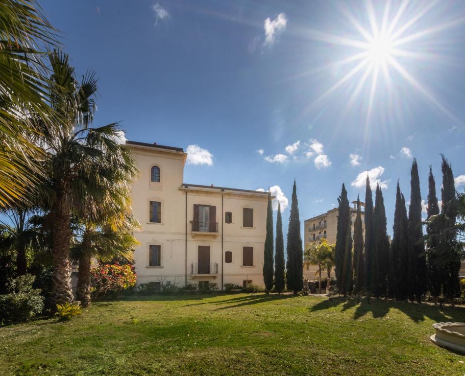 a building with trees and the sun in the sky at Villa Nicolaci - Liberty Suites in Noto