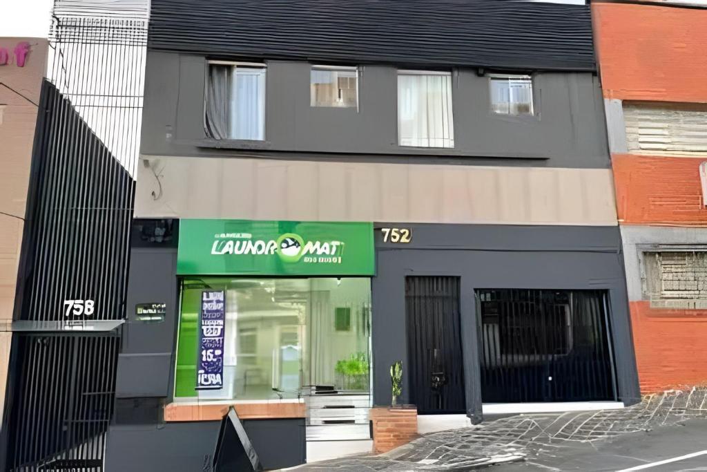a building with a sign in front of a store at Apartamentos centrais junto ao calçadão in Ponta Grossa