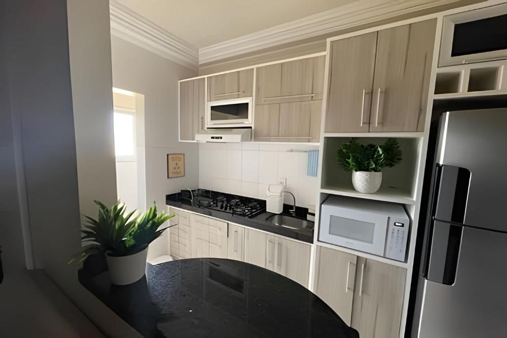 uma cozinha com armários brancos e um balcão preto em Apartamento 2 quartos c/ garagem em Ponta Grossa