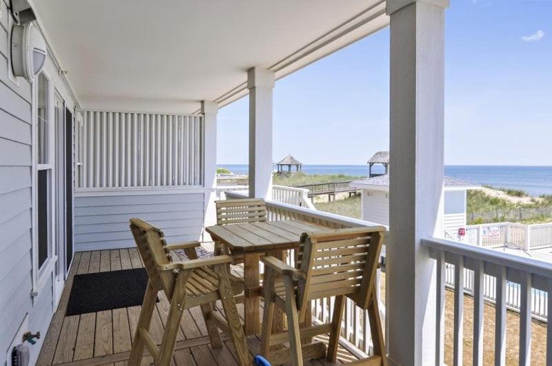 a wooden table and chairs on a porch with the beach at TSC203 Fisher Oceanfront Elevator in Kill Devil Hills