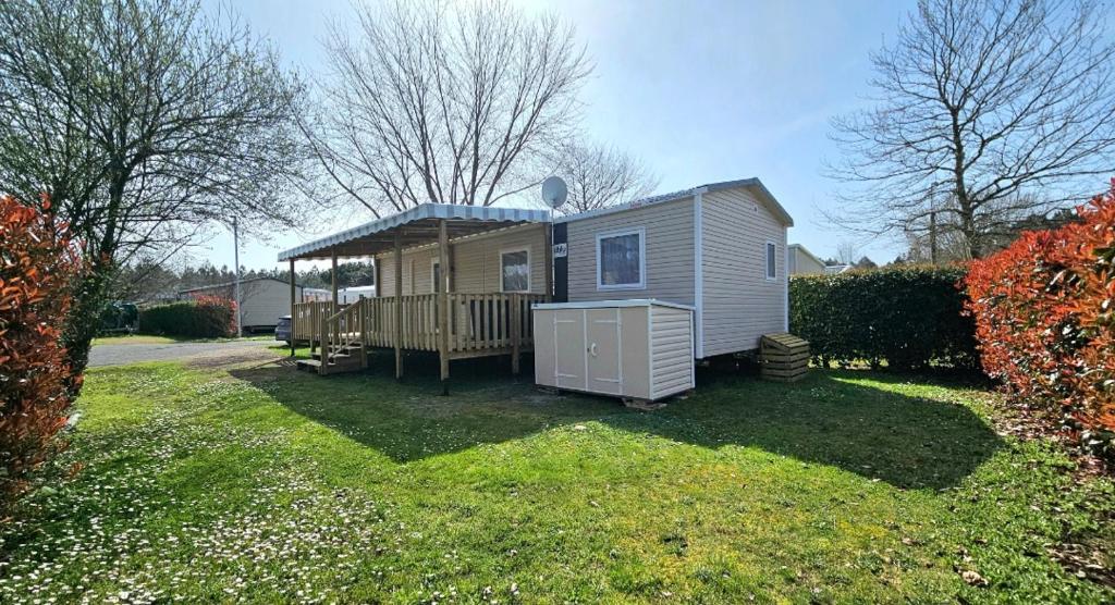 une petite maison avec une terrasse dans une cour dans l'établissement Grand mobil home N°831 tout confort 2ch dans camping 4*, à Gastes