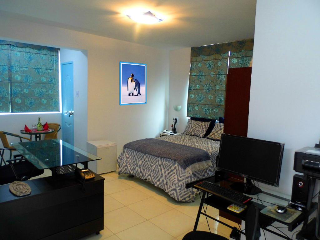 a bedroom with a bed and a desk with a television at Magicperu Apart Hotel in Trujillo
