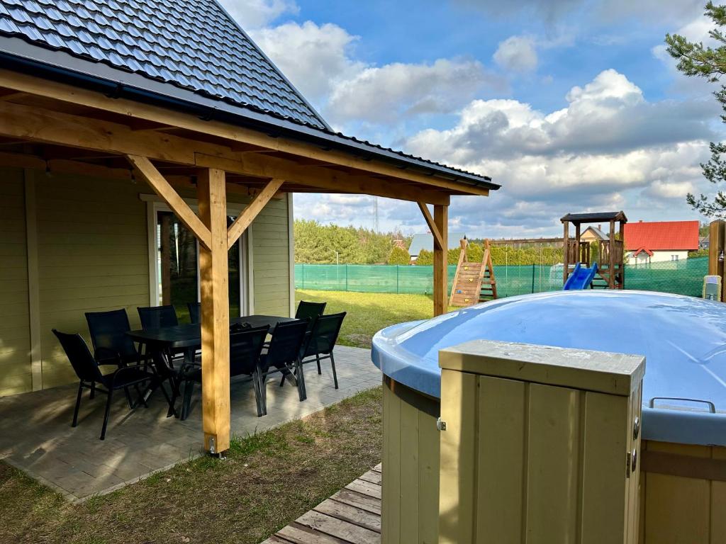 a patio with a hot tub and a table and chairs at Domek Oliwkowy Balia z Jacuzzi KASZUBY in Niesiołowice